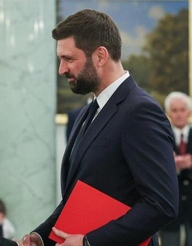Stylizowana scena przedstawiająca dyplomatyczne otoczenie, z elementami symbolizującymi międzynarodowe relacje i politykę, bez postaci.
