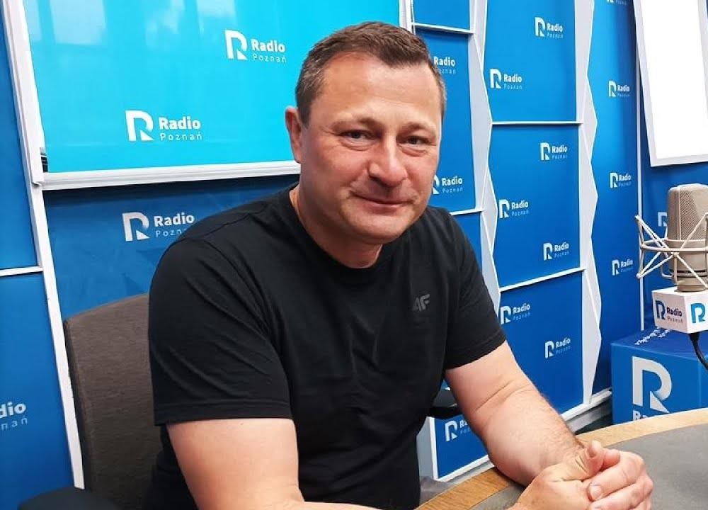 Krzysztof Paszyk podczas wystąpienia publicznego, gestykulujący, na tle rozmytego tłumu lub sali posiedzeń, w trakcie przemówienia.
