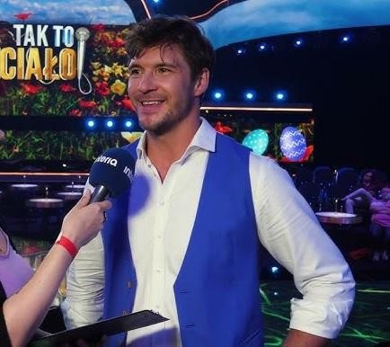 Mikołaj Roznerski w zamyślonej pozie, ukazujący jego siłę i spokój po życiowych wyzwaniach.