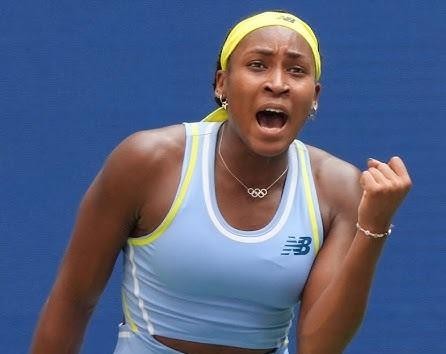 Coco Gauff uśmiechnięta na korcie tenisowym, z rakietą w tle.