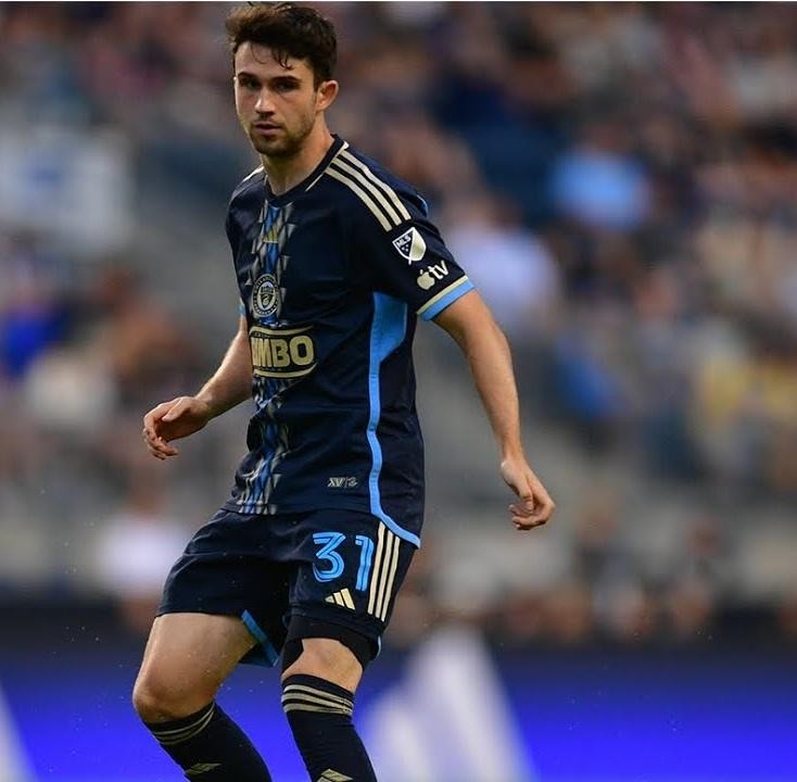Leon Flach w koszulce Philadelphia Union, w akcji na boisku MLS, z innymi zawodnikami w tle.