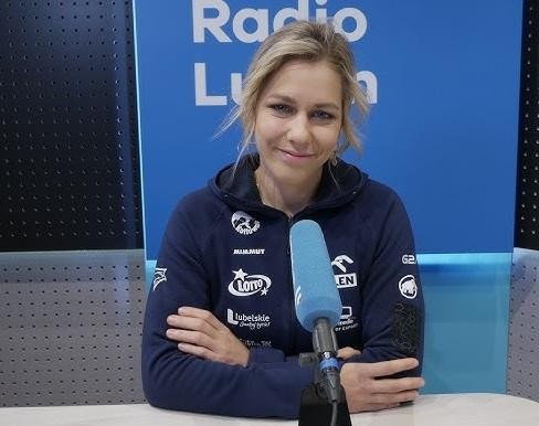 Alt: Aleksandra Mirosław trenująca na 15-metrowej ściance wspinaczkowej w hali sportowej Lubelskiego Uniwersytetu Medycznego, ukazująca skalę miejsca treningowego.