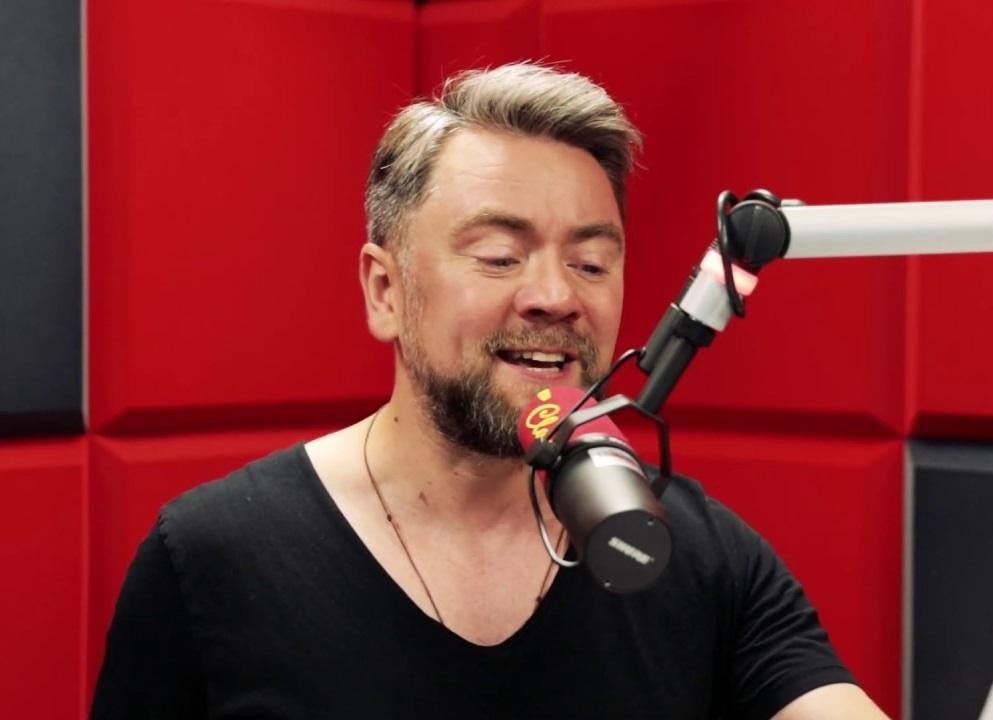 Kuba Badach w trakcie dynamicznego występu na scenie, śpiewający lub grający na instrumencie.