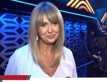 Ewa Wachowicz w eleganckiej kurtce, klasycznych jeansach i szpilkach, prezentująca swój styl i pozytywną energię.