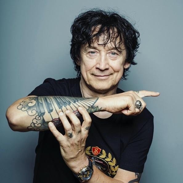 Jan Borysewicz grający na gitarze elektrycznej podczas koncertu Lady Pank, z widocznym tłumem i światłami scenicznymi w tle.