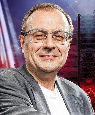 Antoni Dudek podczas wystąpienia publicznego, z widownią w tle, symbolizujący jego aktywność medialną i popularyzację historii.