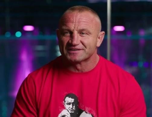 Mariusz Pudzianowski walczący w oktagonie MMA, ukazujący jego siłę i dynamikę w mieszanych sztukach walki.
