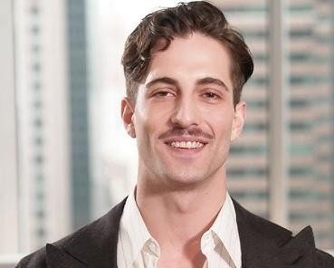 Damiano David na scenie podczas występu, z mikrofonem, w otoczeniu świateł koncertowych, ukazujący swoją energię i pasję.