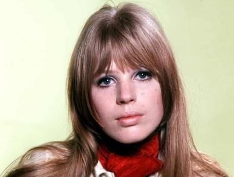 Młoda Marianne Faithfull śpiewająca do mikrofonu w latach 60., w czarno-białym, nostalgicznym ujęciu.